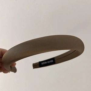 Detail of coffee sponge headband featuring smooth satin fabric and a Hand Made label
