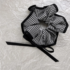 Detail of vintage black and white checkered scrunchie with long ribbon bow decoration