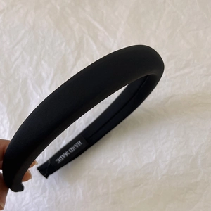 Detail of handmade black padded headband showing soft fabric texture and hand made label