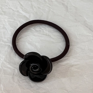 Dettaglio dell'elastico per capelli con fiore di camelia nera e fascia elastica durevole