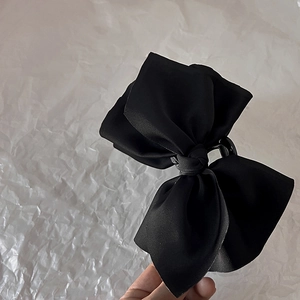 Detailed view of large black satin bow hair claw clip showing elegant fabric texture
