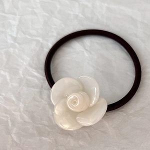 Dettaglio del fiore di camelia in resina bianca su un elastico nero ad alta elasticità