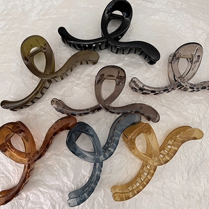 Flat lay detail of large resin hair claws in seven jelly colors on a white background