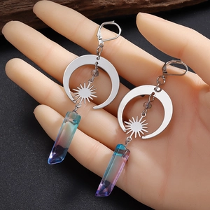 Silberne Keltische Mond und Sonne Ohrringe mit lila-blauen Kristallanhängern in der Hand