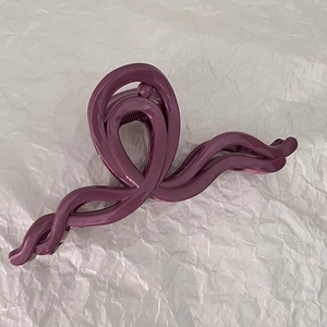 Gros plan d'une pince à cheveux violette brillante avec ressort sur papier plissé