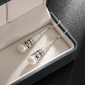 Detailed macro view of vintage crown pearl drop earrings on a premium velvet jewelry box