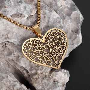 Gros plan du pendentif cœur doré ajouré avec filigrane sur une chaîne à mailles
