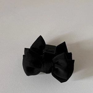 Vue détaillée de la pince à cheveux avec nœud en tissu mat noir sur une surface blanche
