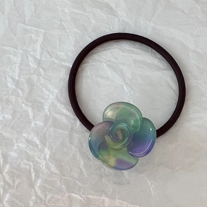 Dettaglio dell'elastico per capelli con camelia sfumata e cinturino nero elastico