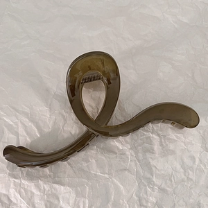Close-up of a large translucent olive green hair claw clip on white wrinkled paper