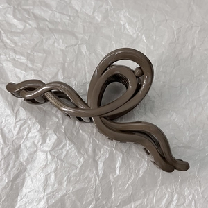Détail d'une grande pince à cheveux marron foncé nacré avec design ondulé en acrylique