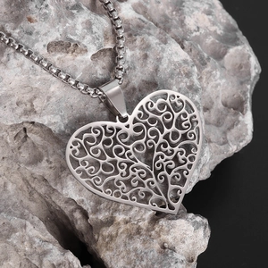 Gros plan du pendentif cœur vintage argenté avec texture filigrane sur support en pierre