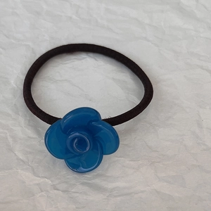 Dettaglio dell'elastico per capelli con fiore in resina blu e gomma nera elasticizzata