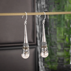 Vintage silver crown earrings with elegant white pearls hanging on a gold jewelry stand