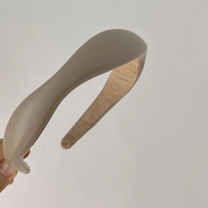 Detailed close-up of beige faux leather headband showing matte texture and padded wave design