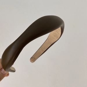 Detailed side view of a brown padded headband with premium faux leather texture