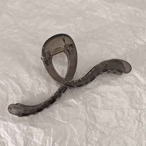 Top view of a minimalist translucent grey hair claw clip on white wrinkled paper background