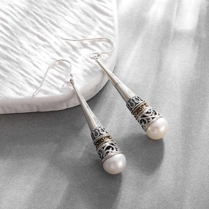 Detailed macro view of vintage crown pearl earrings featuring silver finish and teardrop style