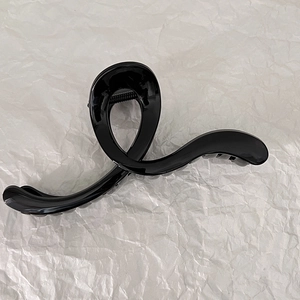 Glossy black hair claw clip with twisted design and metal spring for secure styling