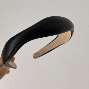 Detail of black padded faux leather headband featuring grainy texture and non-slip lining