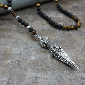 Vue macro d'un pendentif Phurba sur un collier de perles en œil de tigre et lave