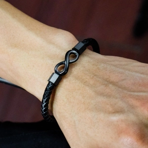 Close-up of black braided leather infinity bracelet with hexagonal beads on a wrist