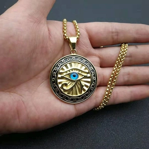 Detail of Eye of Horus pendant with blue evil eye on a gold tone box chain