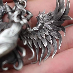 Vintage silver fallen angel wing pendant with detailed feather texture and retro metal finish