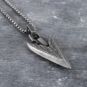 Vintage silver spearhead pendant necklace with Nordic viking design on stone background