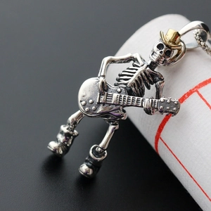 Macro shot of punk skeleton guitar pendant with gold hat and detailed metal texture