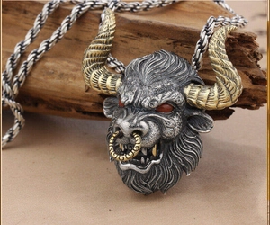 Détail macro du pendentif tête de taureau avec cornes dorées et yeux rouges sur bois