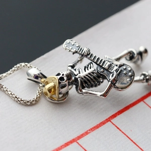 Detailed macro view of a punk rock skull guitar pendant with gold hat and silver finish