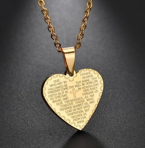 Gros plan détaillé du pendentif cœur doré avec croix et texte gravé du Notre Père