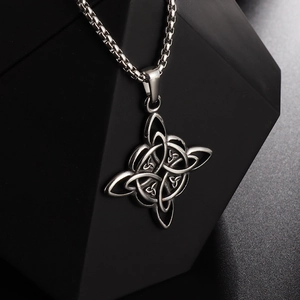 Macro side view of silver Celtic Knot pendant with box chain on a geometric stand