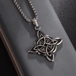 Macro shot of stainless steel Celtic Witch's Knot pendant with antique silver finish on grey box