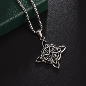 Close-up of vintage silver Celtic knot pendant with box chain on a green jewelry box