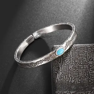 Detailed close-up of vintage silver open cuff with turquoise and floral engraving