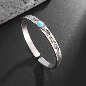 Detail of vintage carved silver bangle with intricate feather texture and turquoise stone