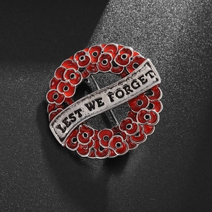 Macro shot of red poppy enamel brooch with silver banner and Lest We Forget engraving