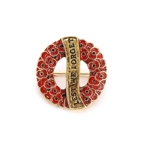 Macro detail of red enamel poppy wreath brooch with Lest We Forget gold engraving
