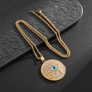 Gros plan du pendentif Œil d'Horus doré avec œil bleu et strass scintillants sur fond noir