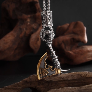 Detalle macro del colgante de hacha vikinga con símbolo Valknut y detalles en oro sobre madera