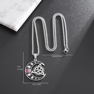 Macro shot of silver crescent moon necklace with Celtic knot and pink gem detail