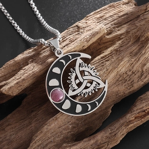 Macro view of stainless steel crescent moon pendant with celtic knots on dark wood