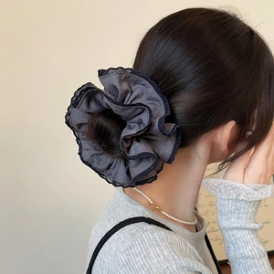 Elegant grey pleated scrunchie with black lace trim on a low bun hairstyle