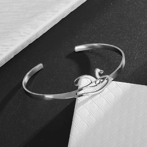 Detailed macro view of silver stainless steel open bangle with hollow swan design