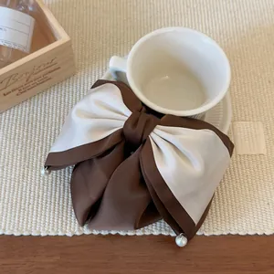 Détail de la pince à cheveux en satin bicolore marron et beige avec perles élégantes
