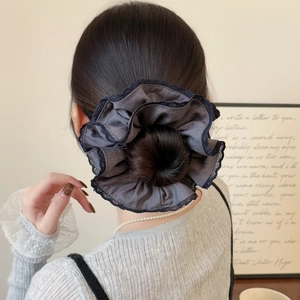 Grey oversized pleated hair scrunchie with black lace trim on a stylish bun hairstyle