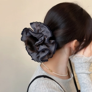 Deep grey oversized scrunchie with delicate black lace trim shown in a low bun hairstyle