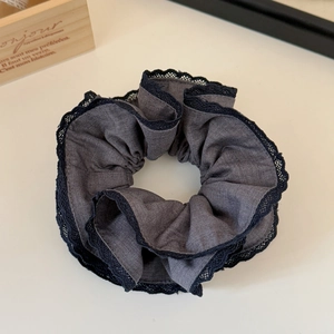 Detailed close-up of charcoal grey scrunchie with delicate black lace trim and soft fabric